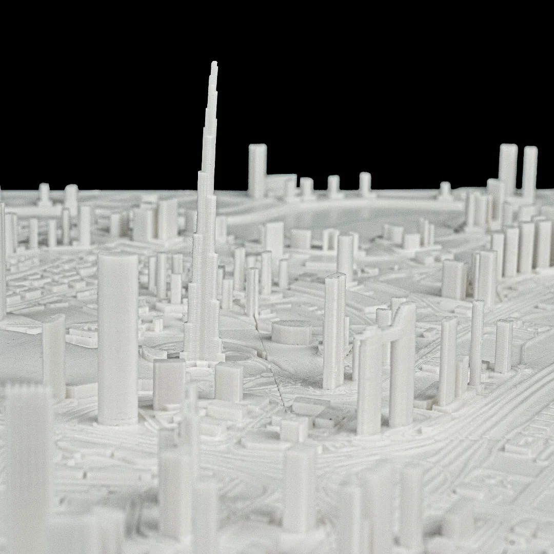 Low angled view of a Dubai relief map showing a tall tower and surrounding buildings.