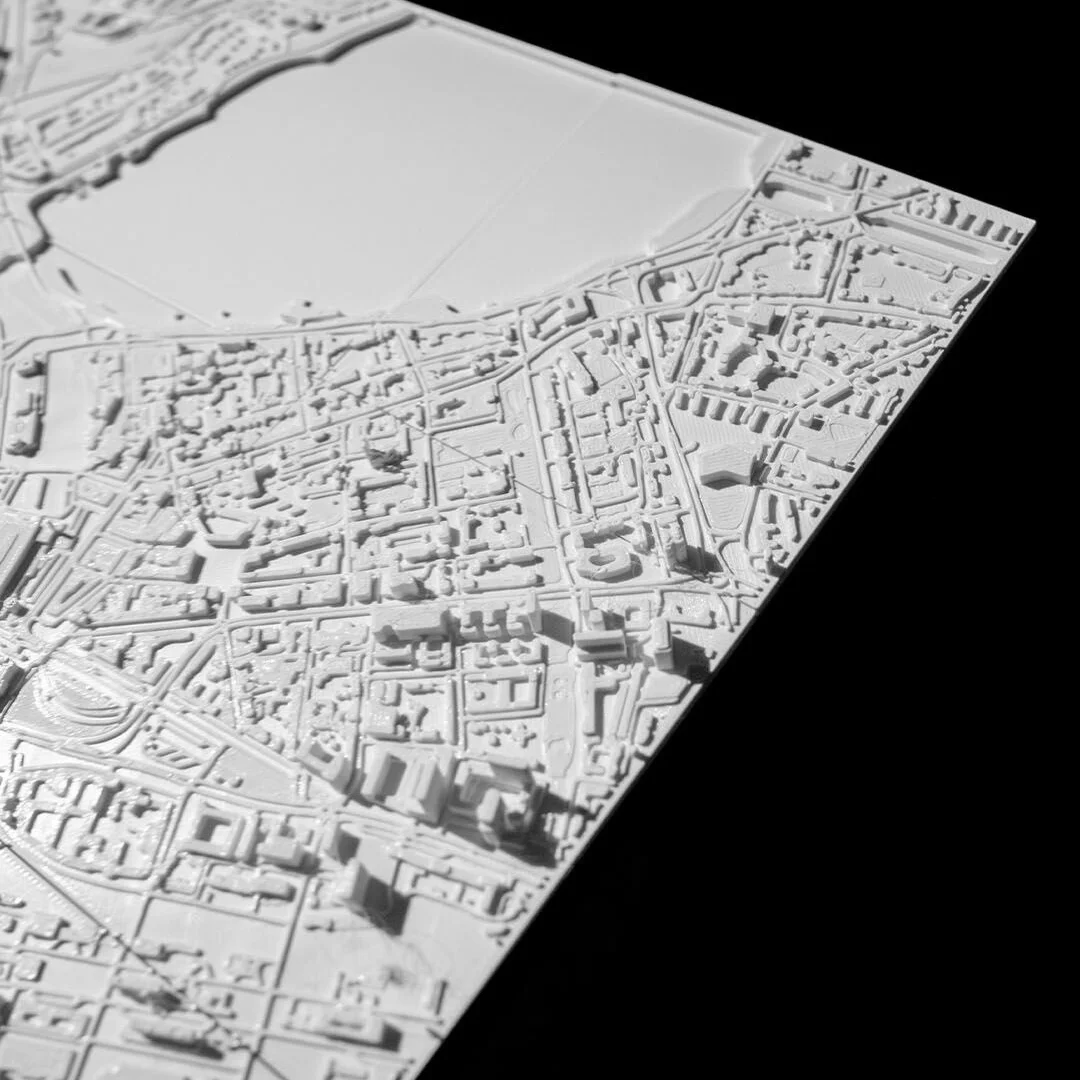 Angled overhead view of a Hamburg city relief map beside a broad water feature.
