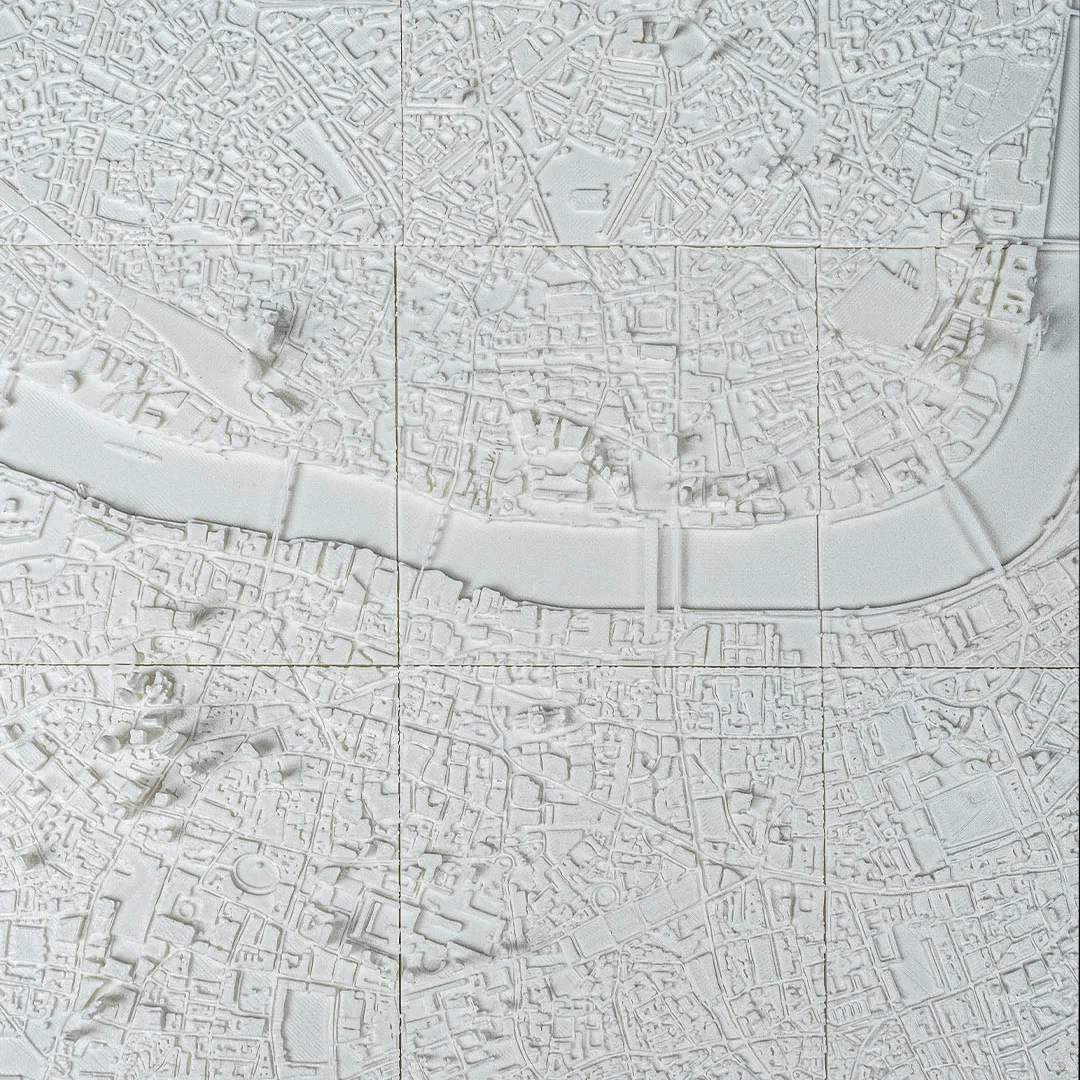 Wide overhead detail of streets and buildings beside the river in a London relief map.