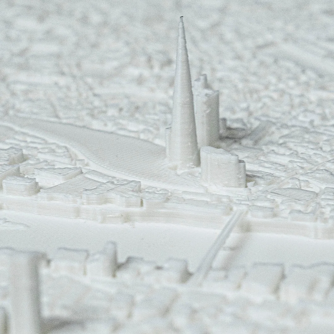 Close view of a pointed skyscraper beside the river in a London city relief map.