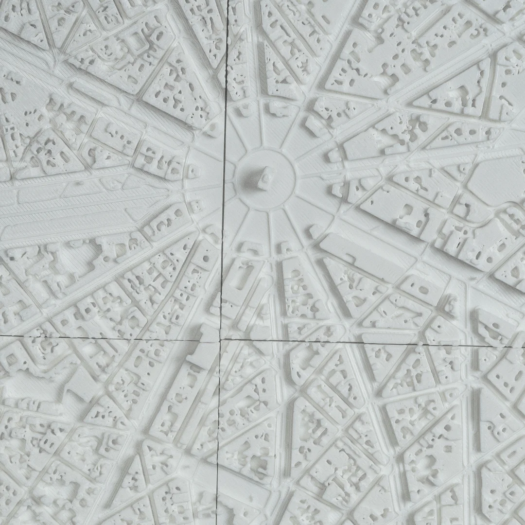 Overhead detail of radial avenues and raised buildings in a Paris city relief map.