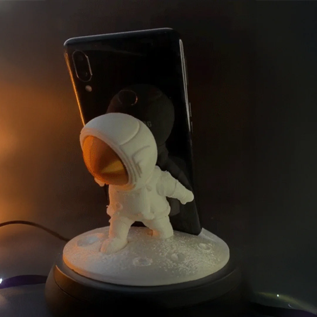 Front angled view of an astronaut phone holder with a smartphone behind the figure.