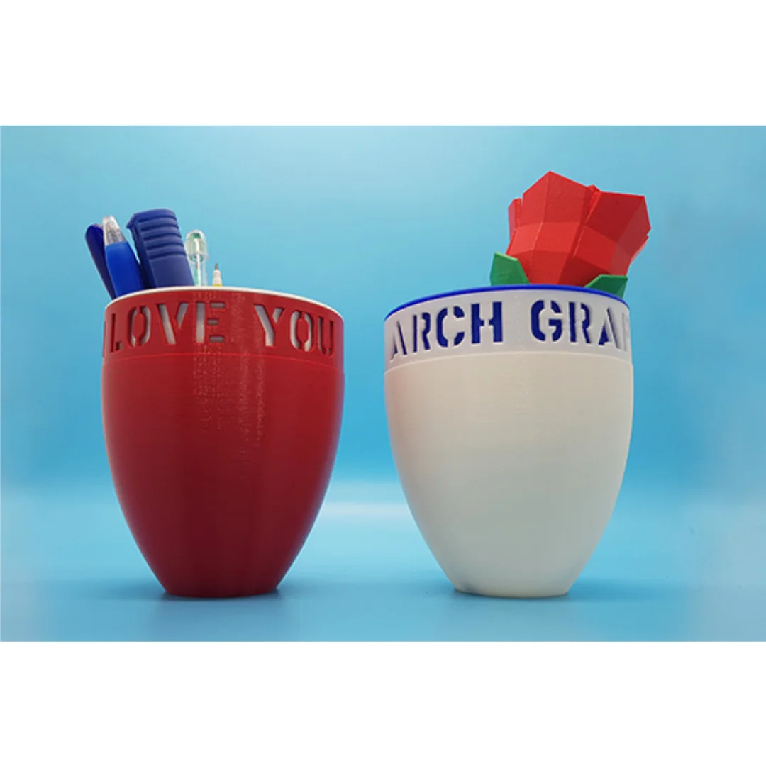 Personalised mug-shaped desk holders displayed with pens and a decorative rose.