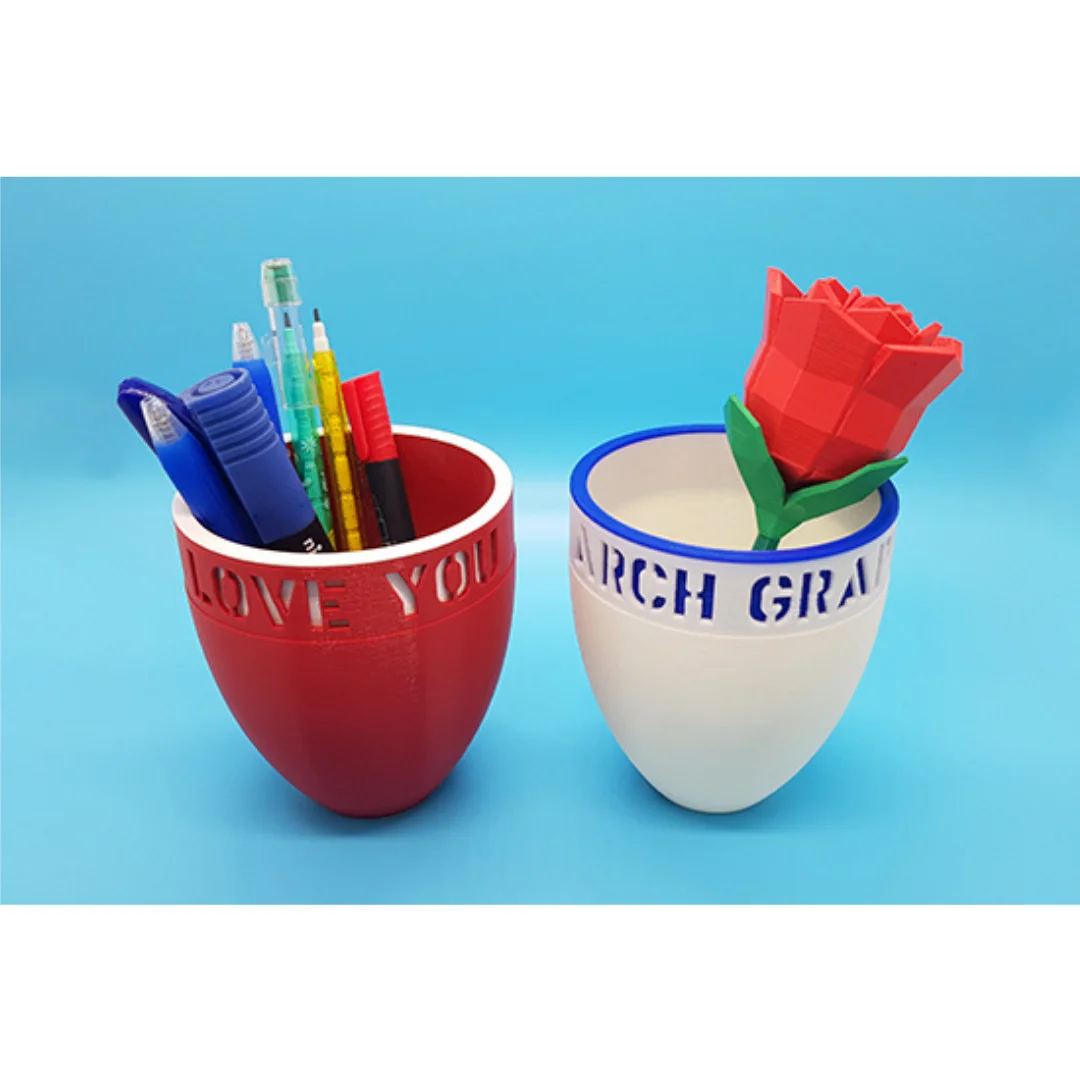 Angled view of two personalised desk mugs holding stationery and a decorative rose.