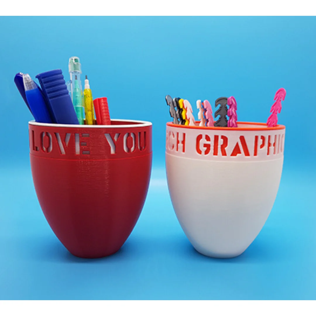 Two personalised desk mugs holding pens and decorative toppers.