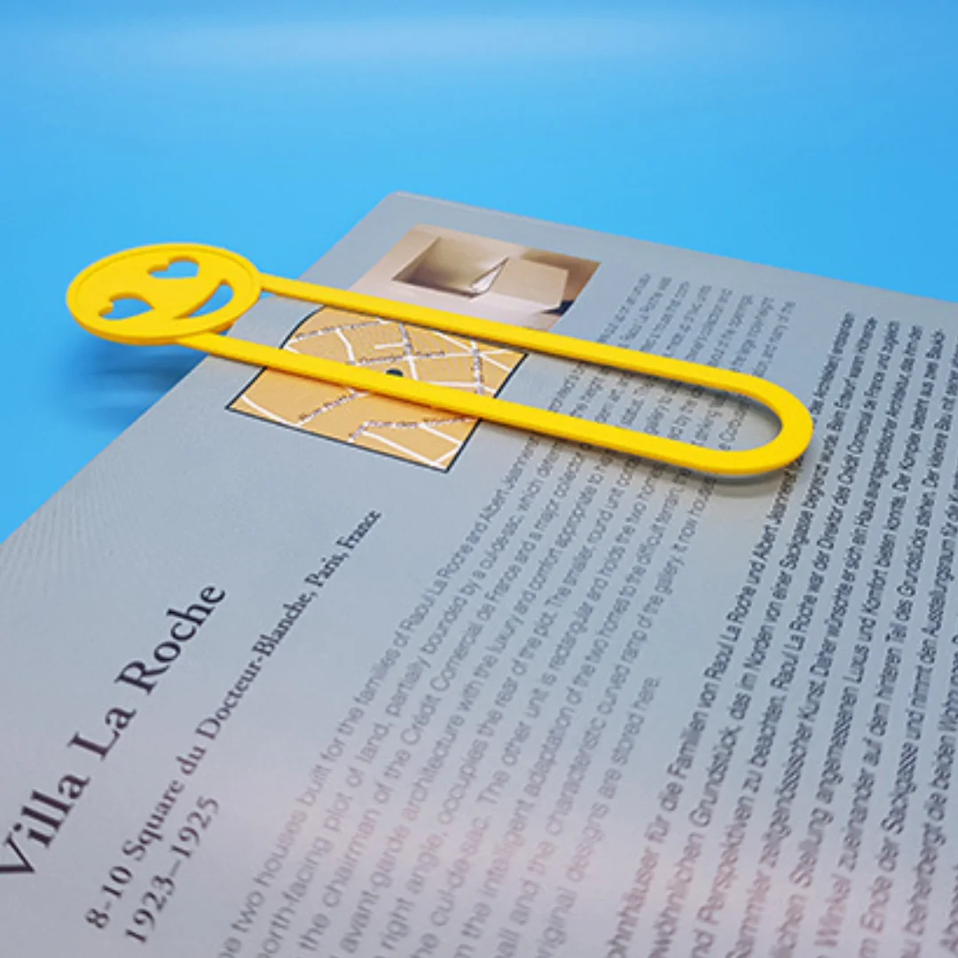 Single emoji bookmark resting across an open book page.