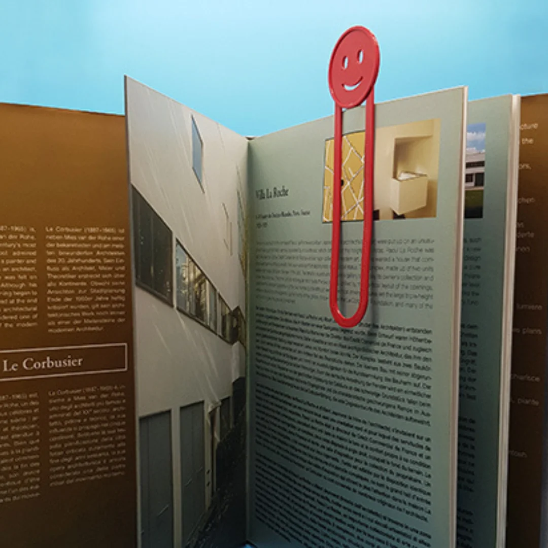 Smiling emoji bookmark marking a page in an upright open book.