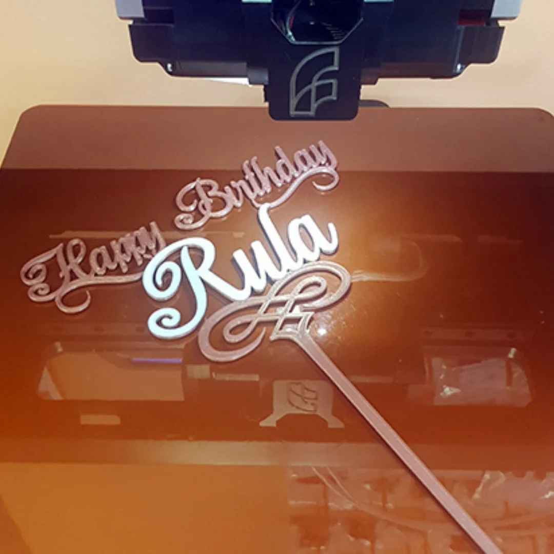 Close view of a personalised birthday name cake topper on a 3D printer build plate.