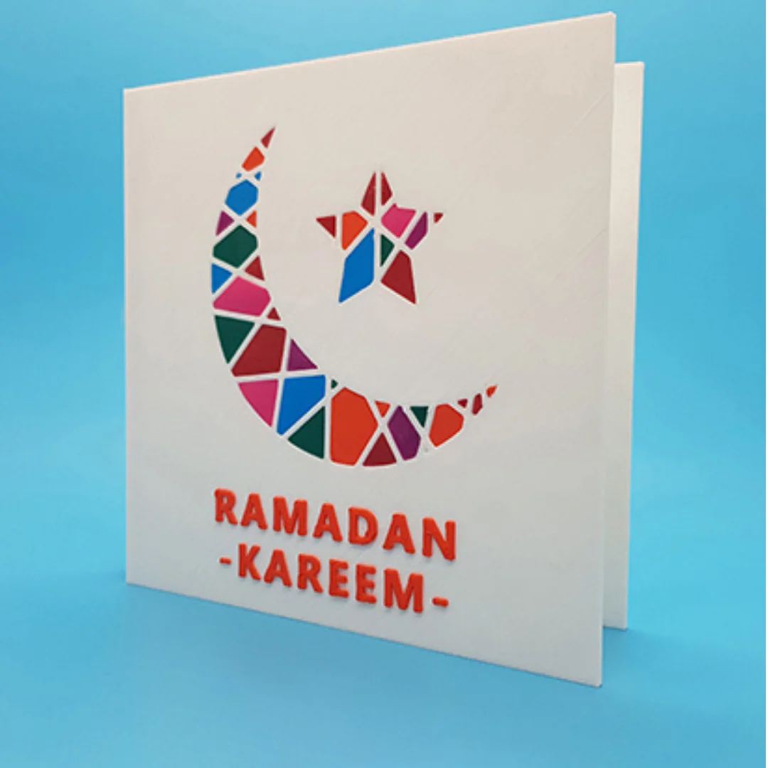 Ramadan Kareem card standing partly open, showing the crescent and star on the front.