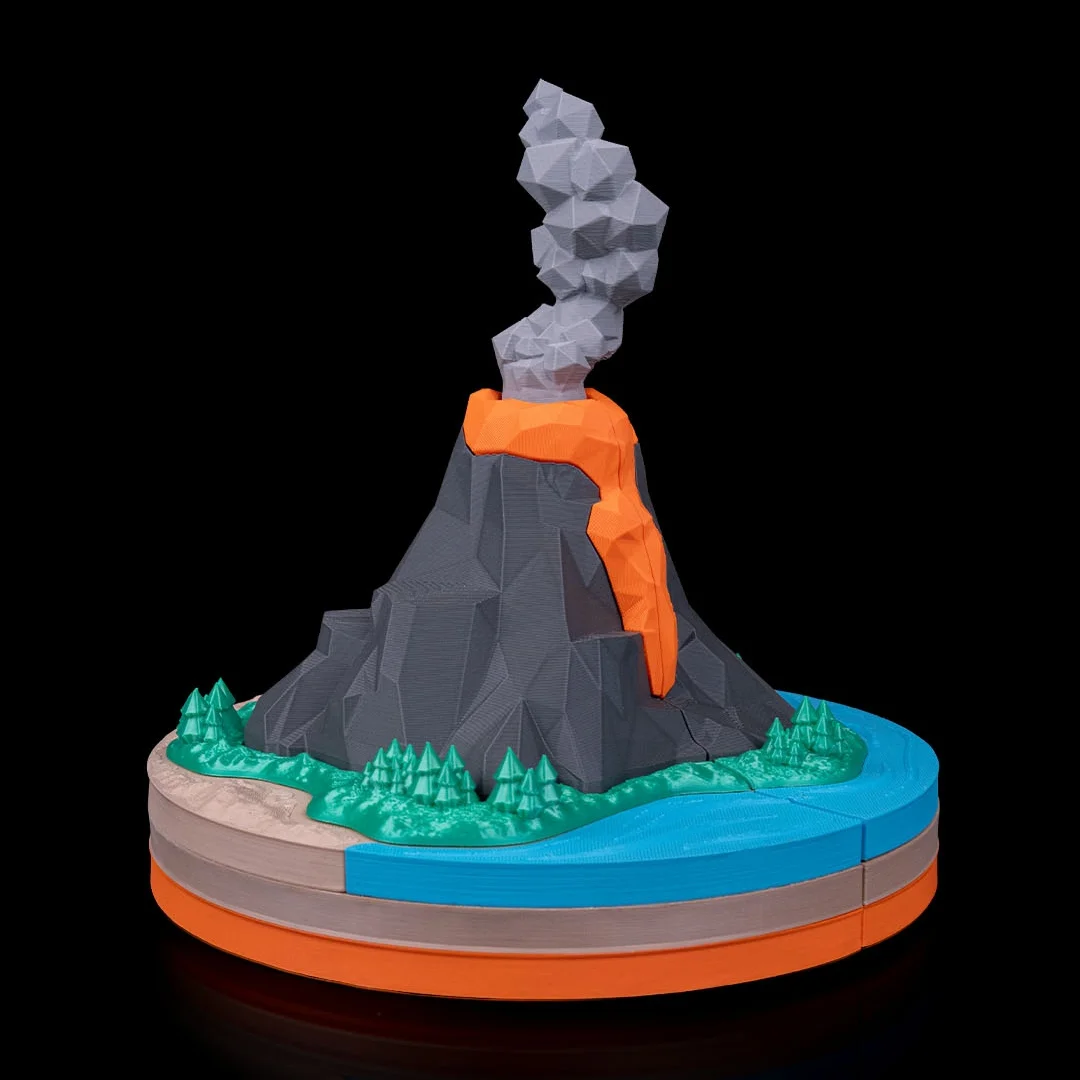 Angled view of a volcano model with water and trees around the base.