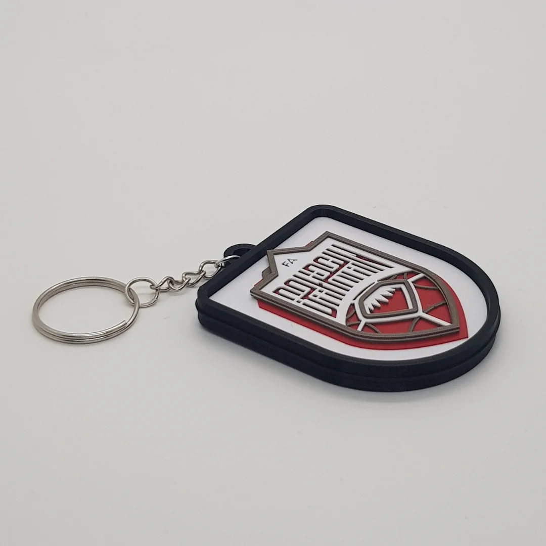 Angled front view of a Bahrain football keychain showing the raised crest and metal key ring.