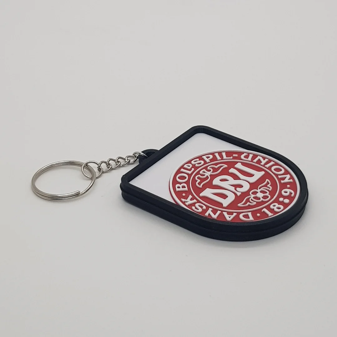 Angled front view of a Denmark football keychain showing the raised crest and metal key ring.