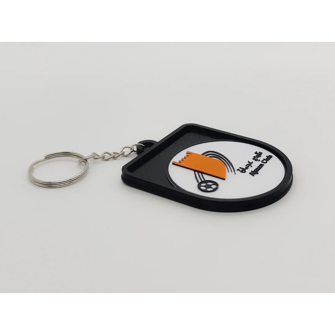 Angled view of the Ajman Club keychain showing its raised club crest and key ring.