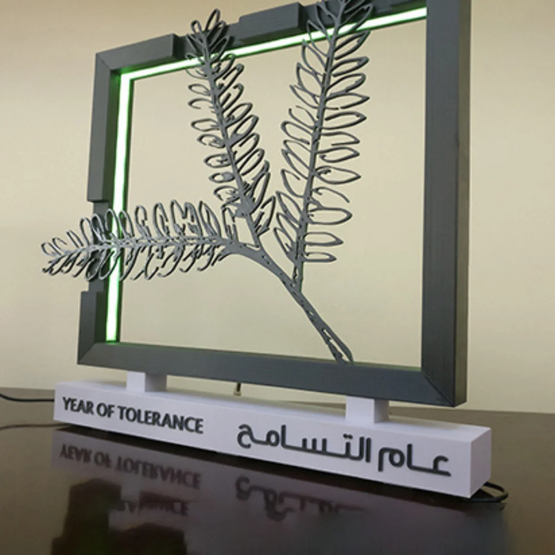 Year of Tolerance branch sculpture inside an illuminated square frame on a bilingual display base.