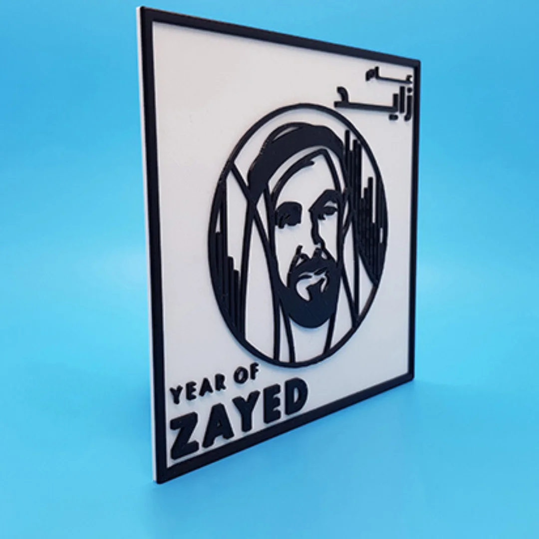 Angled view of a Year of Zayed plaque with a raised portrait and Arabic and English lettering.